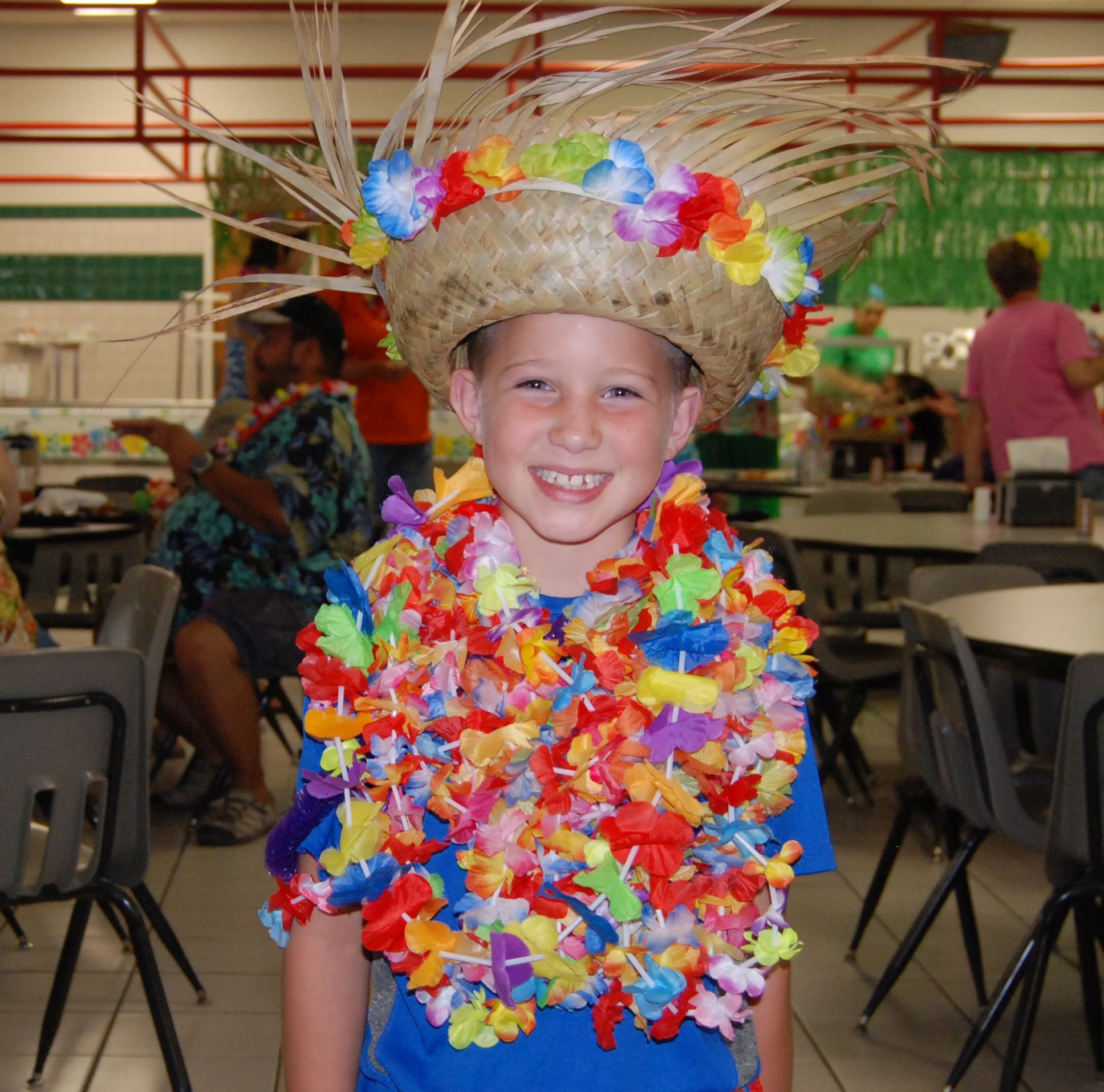 A camper in a straw hat and colorful leis grins during Luau Night.