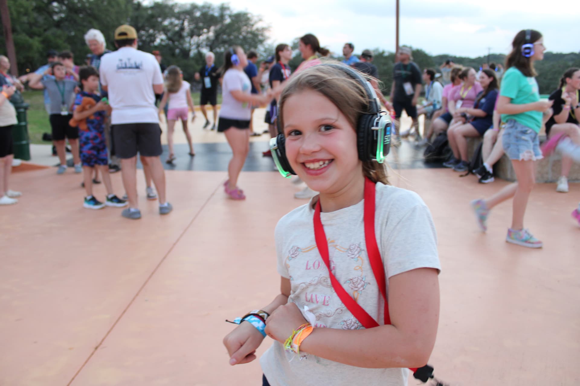 A camper wearing glowing headphones smiles during a silent disco at camp.