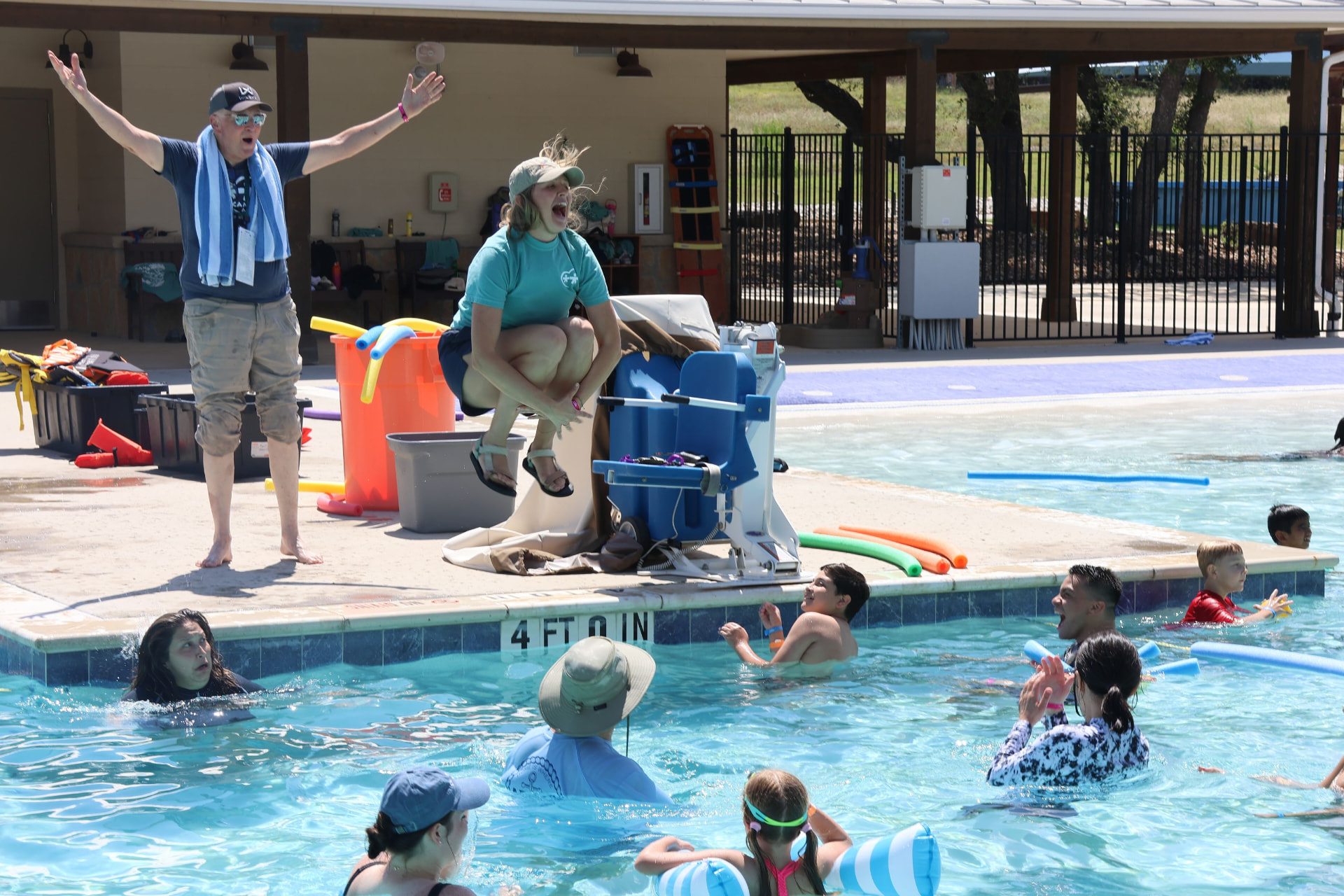 A volunteer cannonballs into the camp pool while campers cheer.