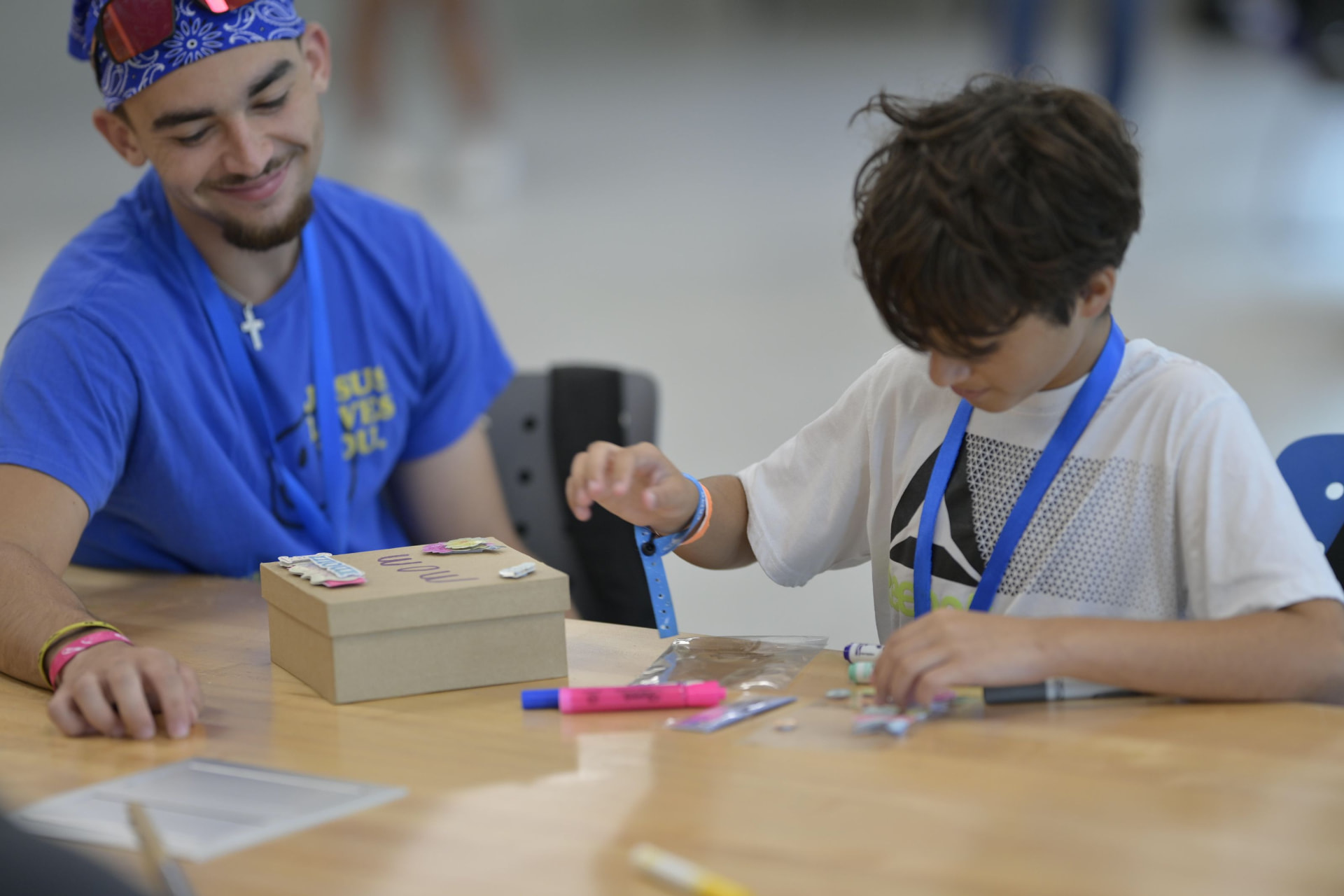 A volunteer facilitator helps a camper decorate a memory box during a Camp in a Box activity.
