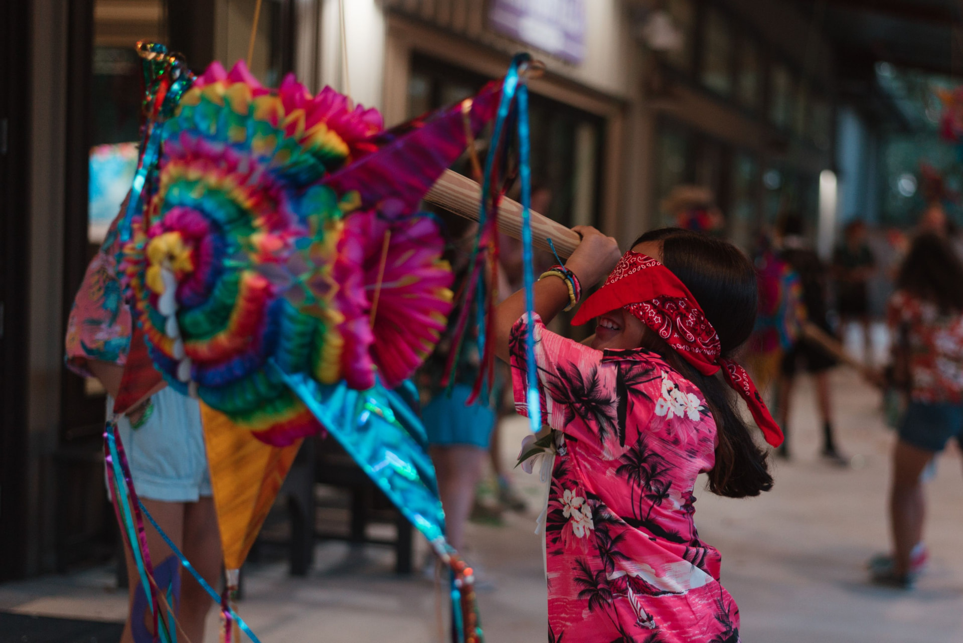 A blindfolded camper swings at a bright piñata at camp.